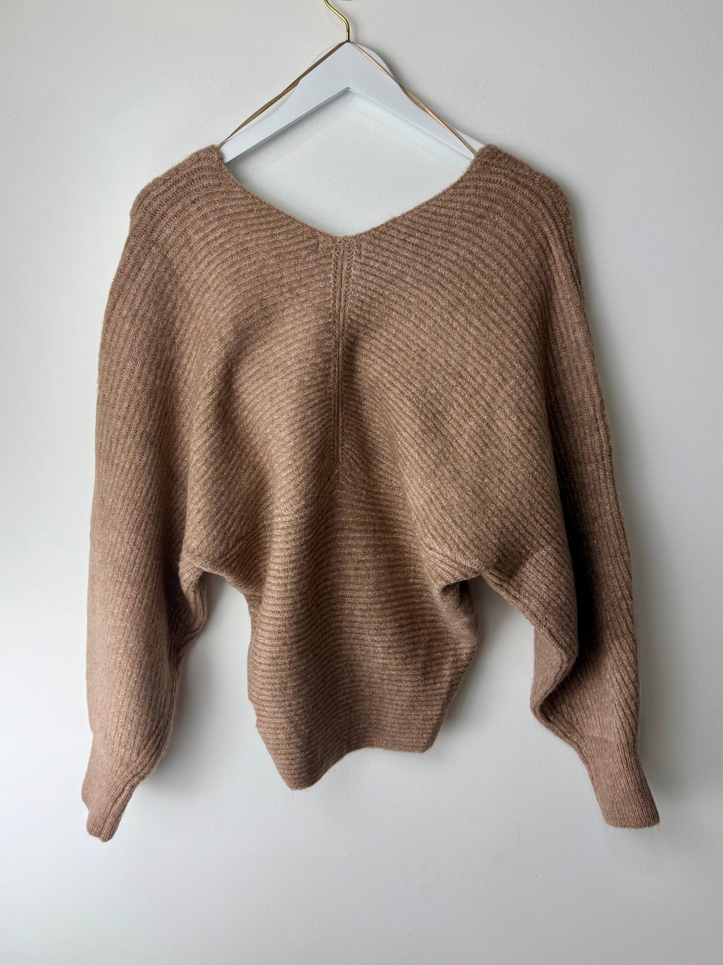 Brown sweater on a white hanger against a white background