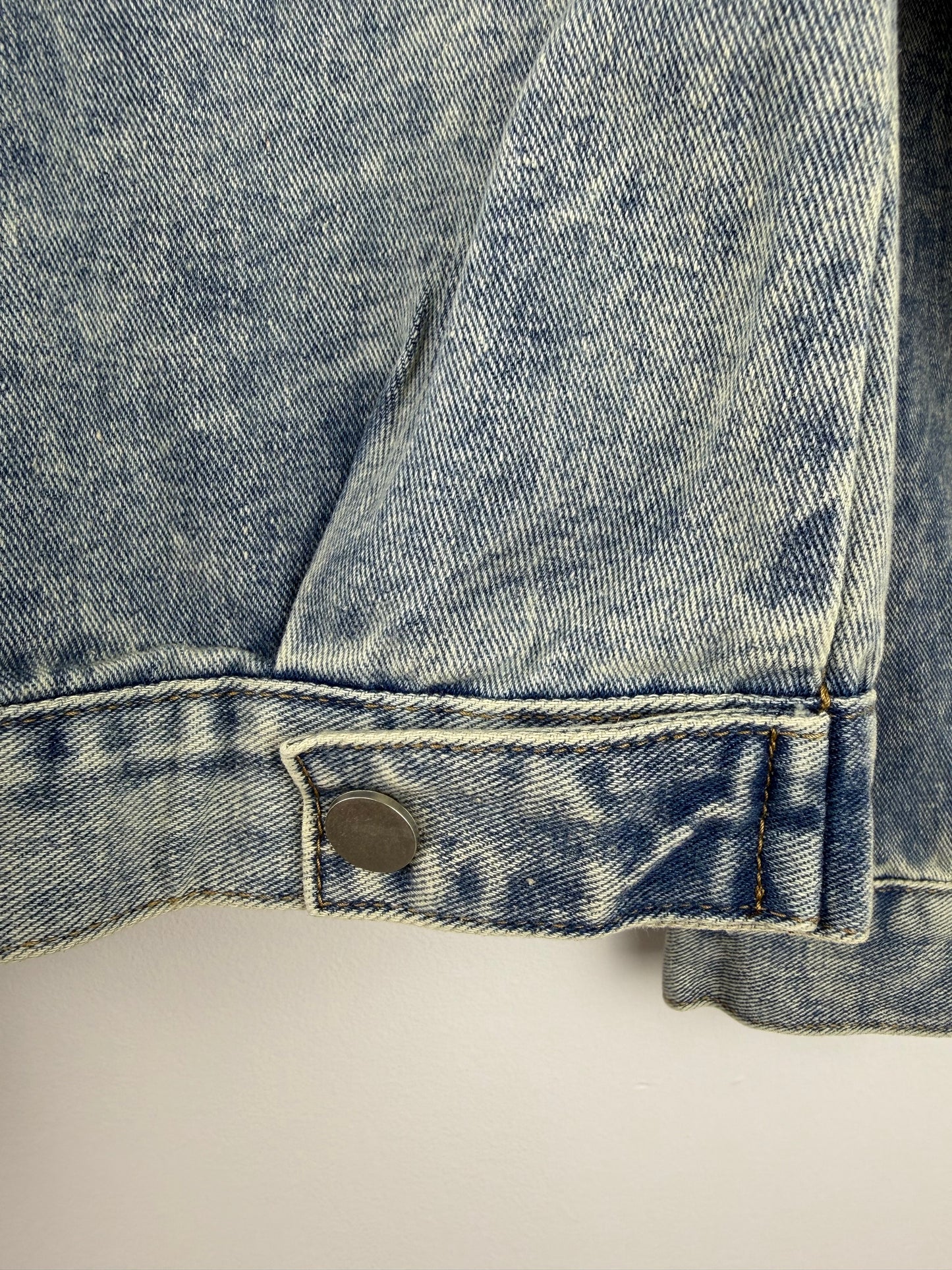 Close-up of a blue denim pocket with a brand label on a light gray background