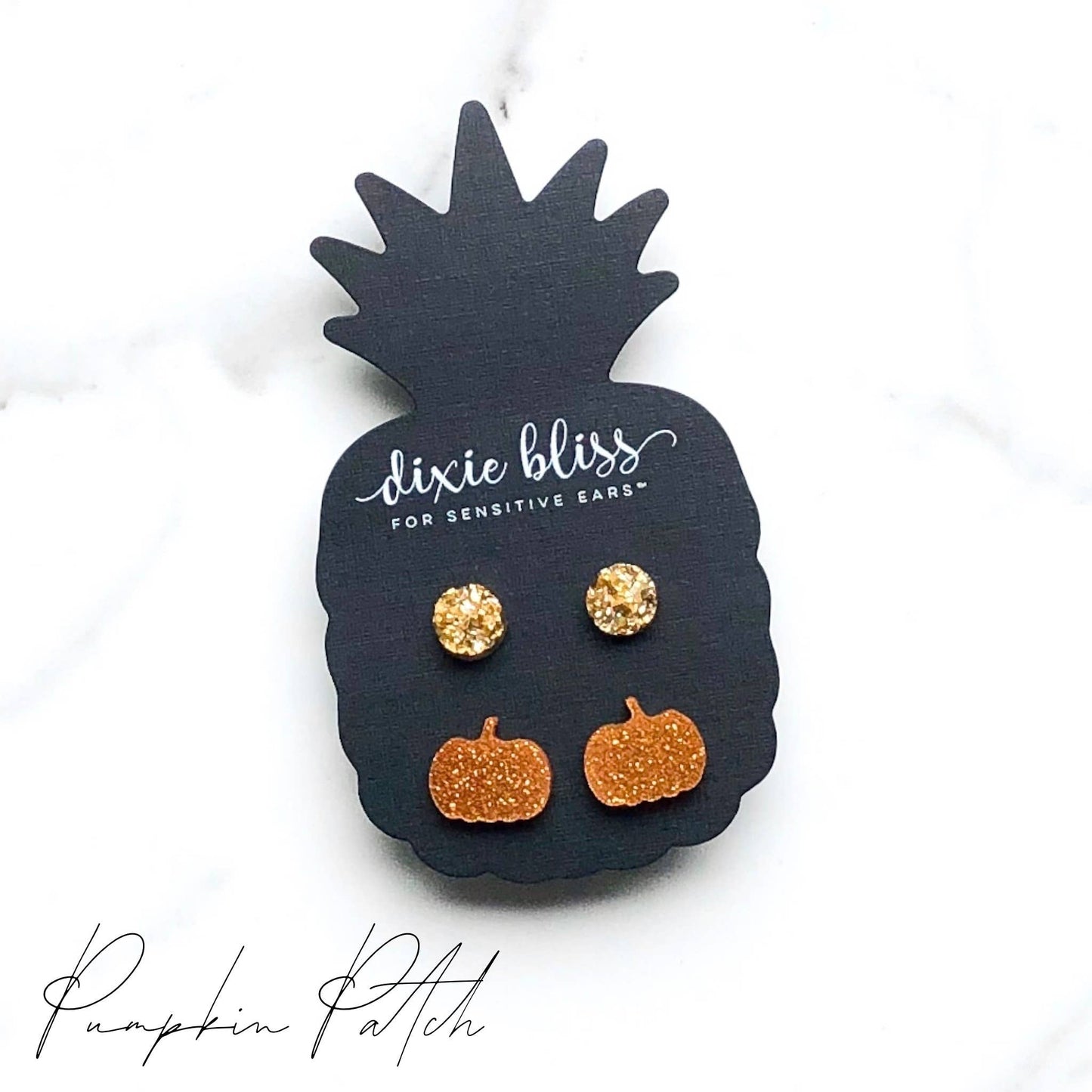 Gold pumpkin-shaped earrings on a black pineapple-shaped card with 'dixie bliss' branding.