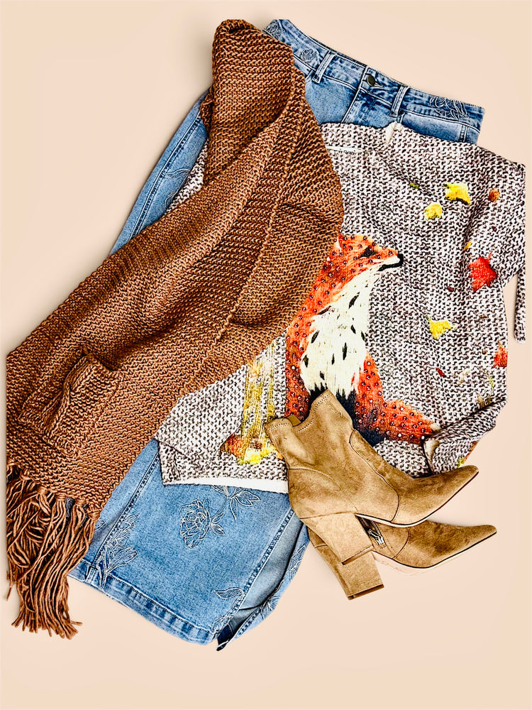 Flatlay of brown scarf a boot and a fox graphic sweatet