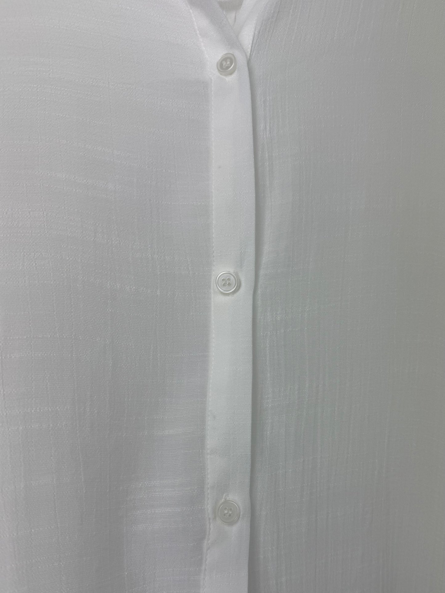 Close-up of a white button-up shirt with a plain background