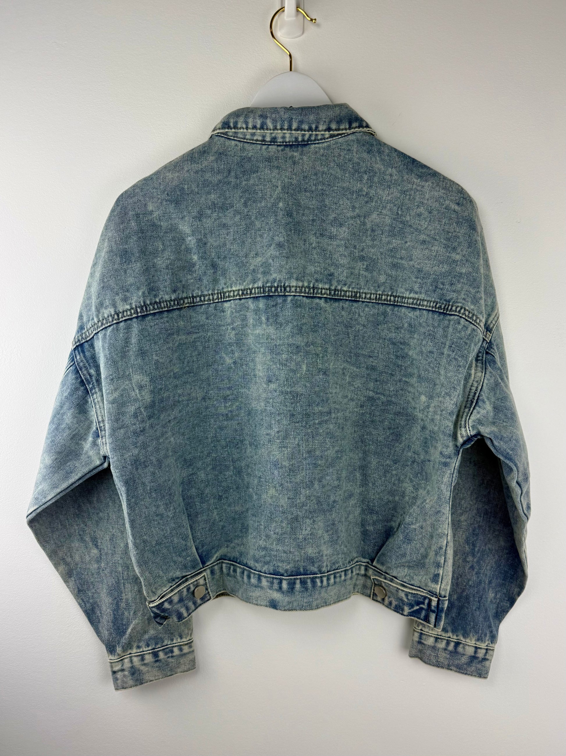Blue denim jacket on a white hanger against a white background