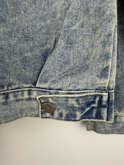Close-up of a blue denim pocket with a brand label on a light gray background