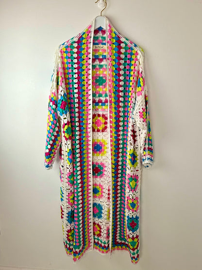 Colorful crochet cardigan on a hanger against a white background