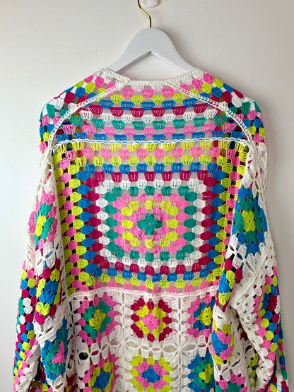 Colorful crocheted sweater on a hanger against a white background
