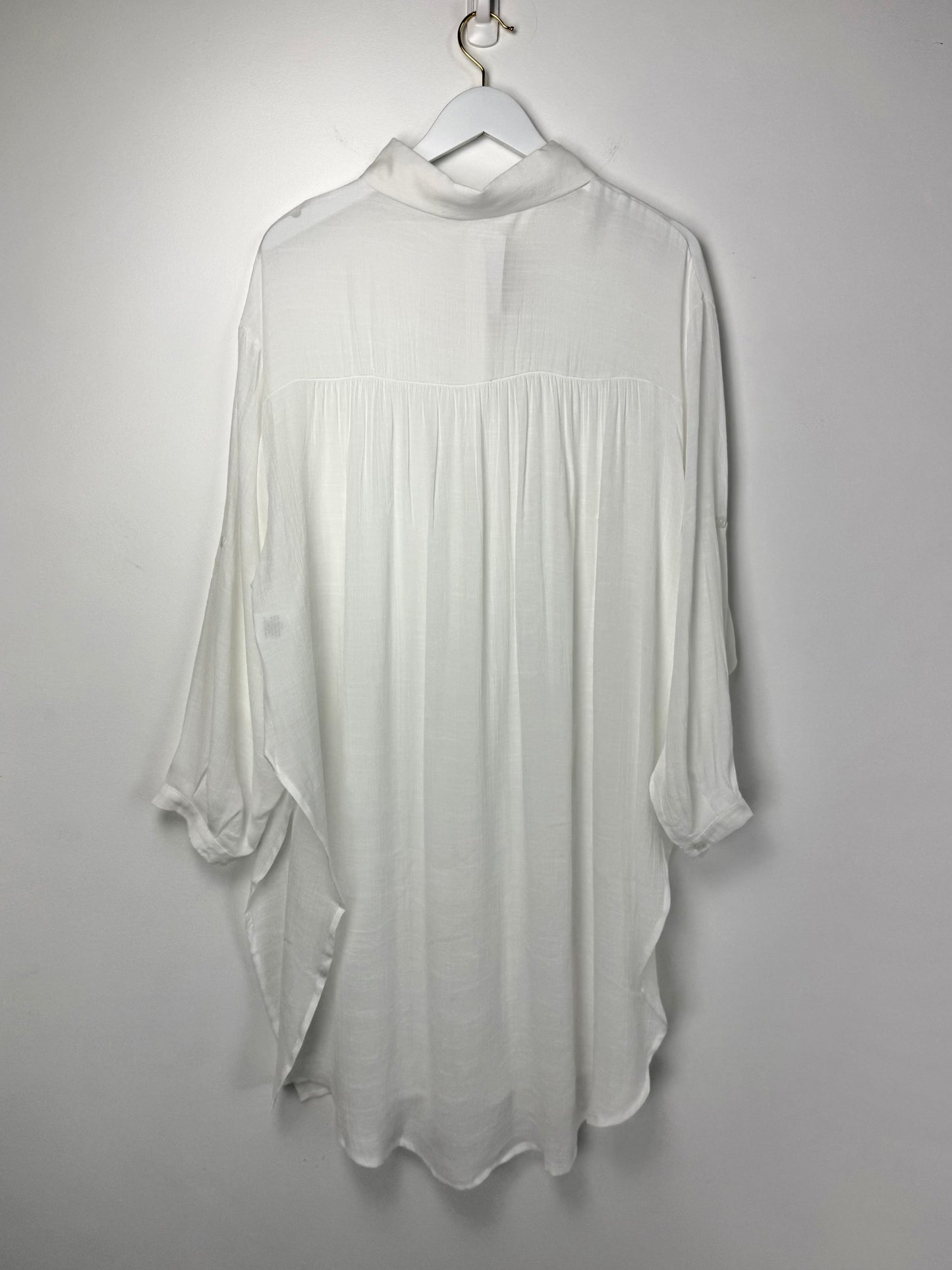 White blouse on a hanger against a plain background