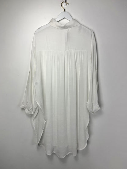 White blouse on a hanger against a plain background