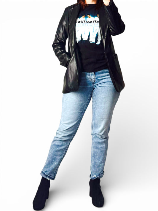 Person wearing a black leather jacket, black graphic t-shirt, and light blue jeans on a white background