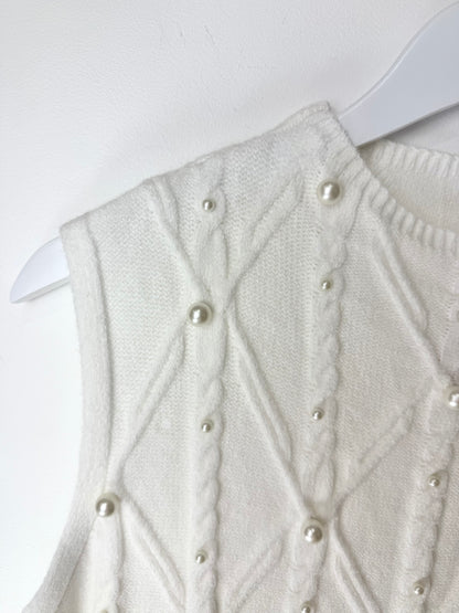 White knitted vest with pearl buttons on a white background
