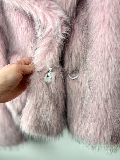 Close-up of a pink fur coat with a hand touching the fabric.