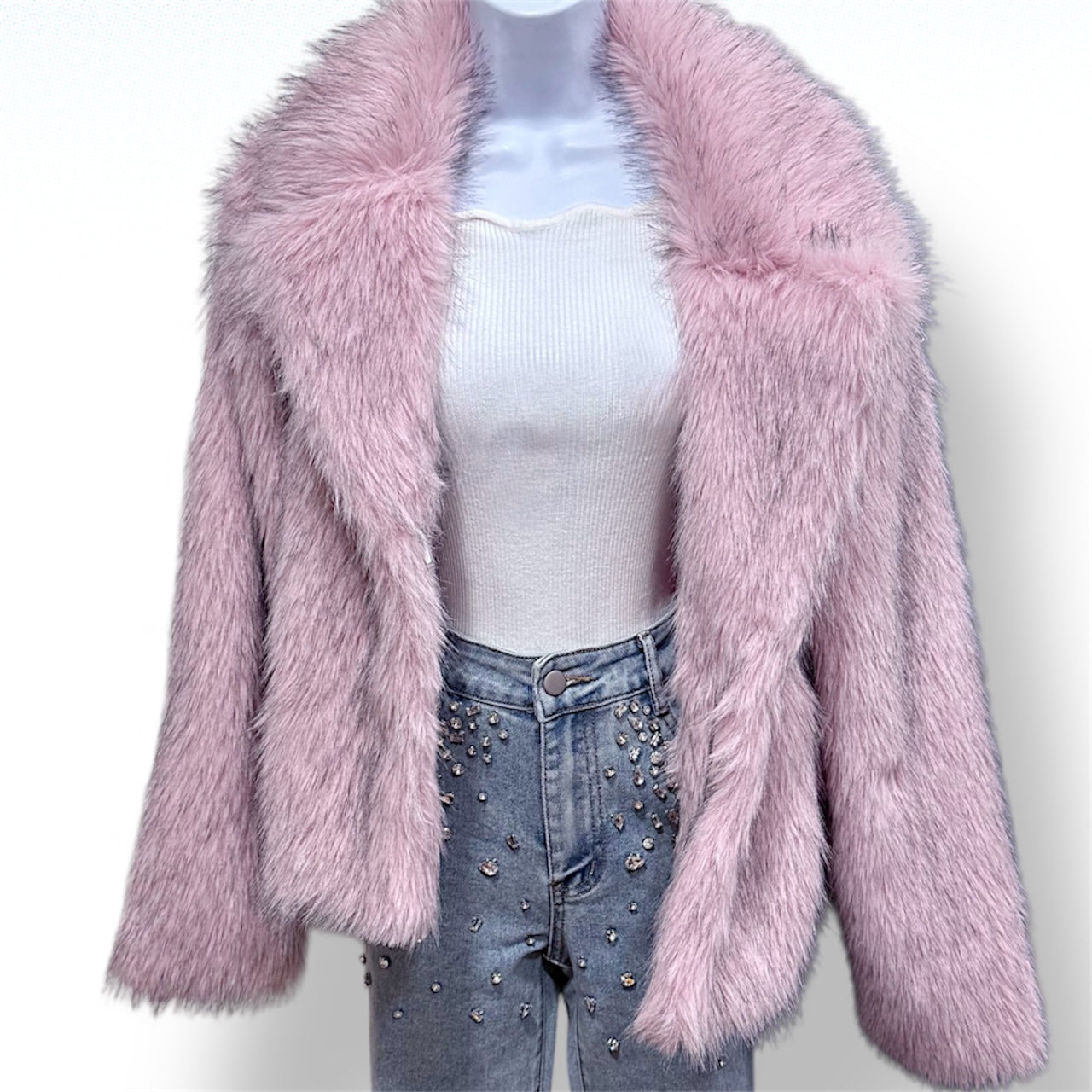 Pink fluffy jacket worn over a white top and blue jeans with studs on a white background