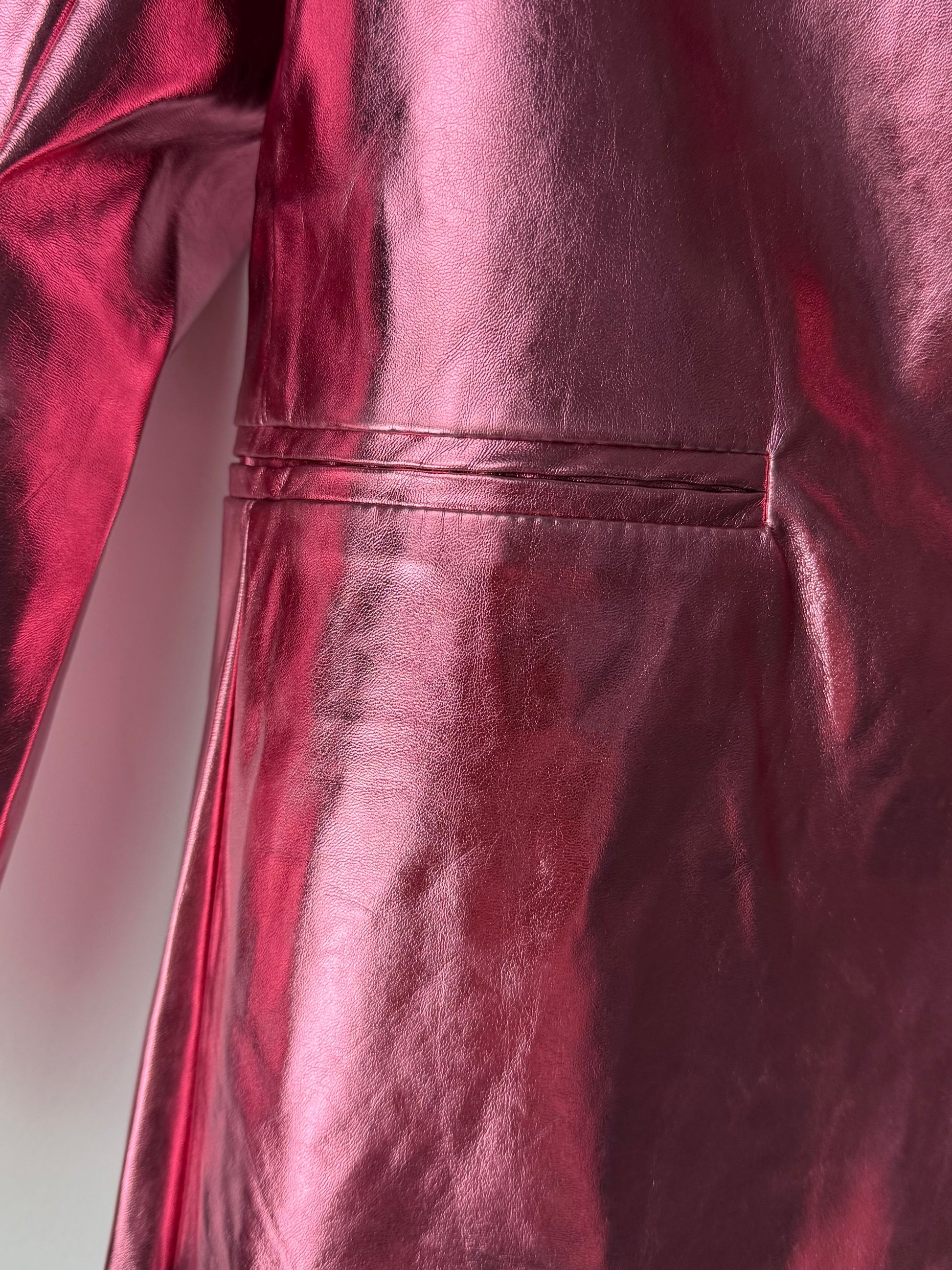 Close-up of a shiny metallic pink blazer with a plain background