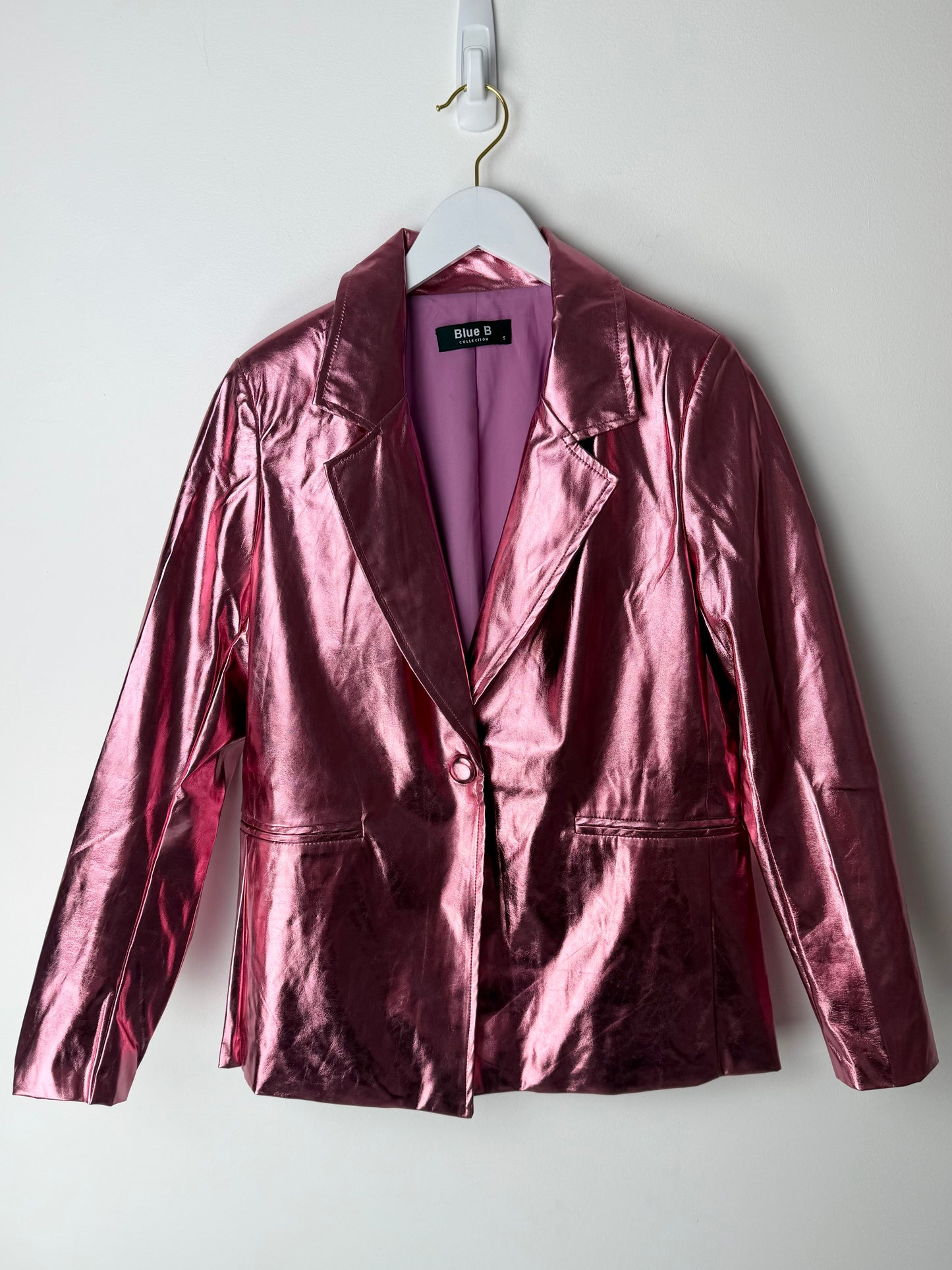 Edgy glam Pink metallic jacket on a hanger against a white background