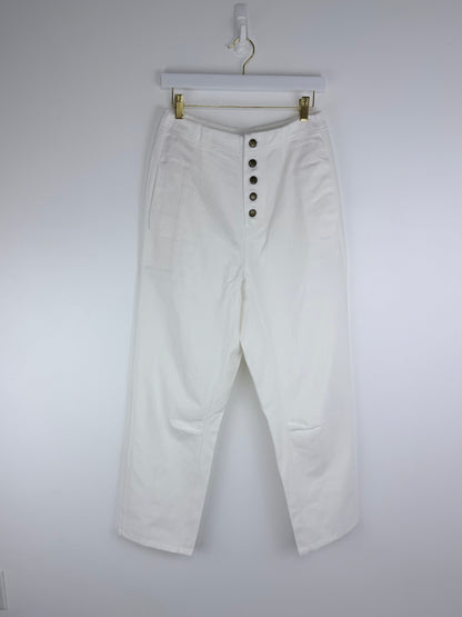 White pants with button details on a hanger against a white background