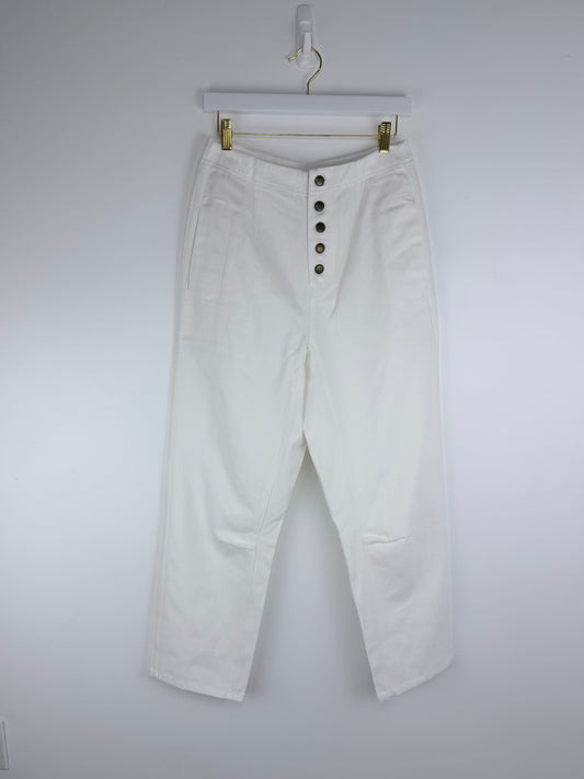 White pants with button details on a hanger against a white background