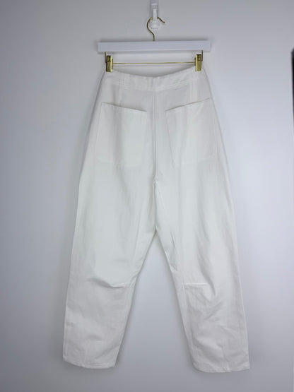 White pants hanging on a hanger against a plain background