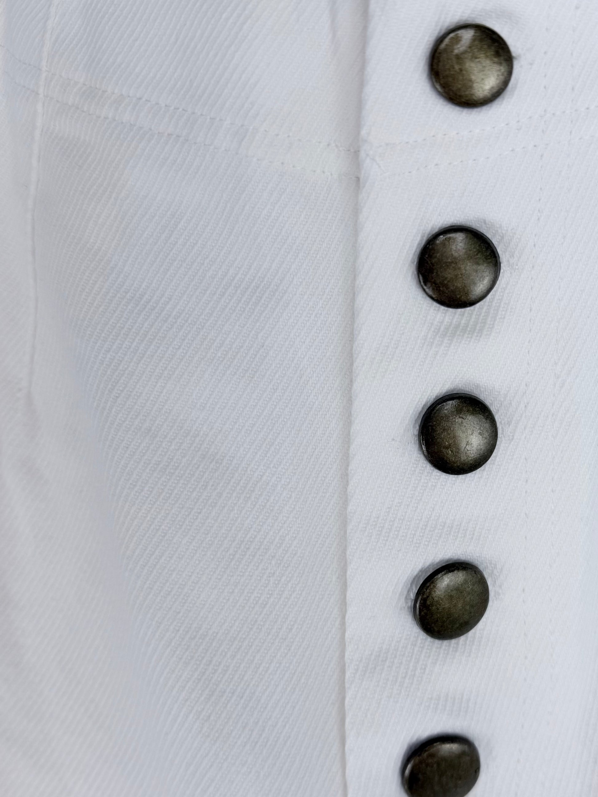 Close-up of white jeans with dark buttons on a white background