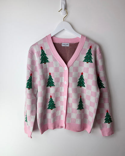 Pink checkered cardigan with Christmas tree patterns on a white hanger against a white background