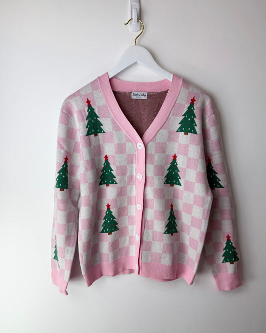 Pink checkered cardigan with Christmas tree patterns on a white hanger against a white background