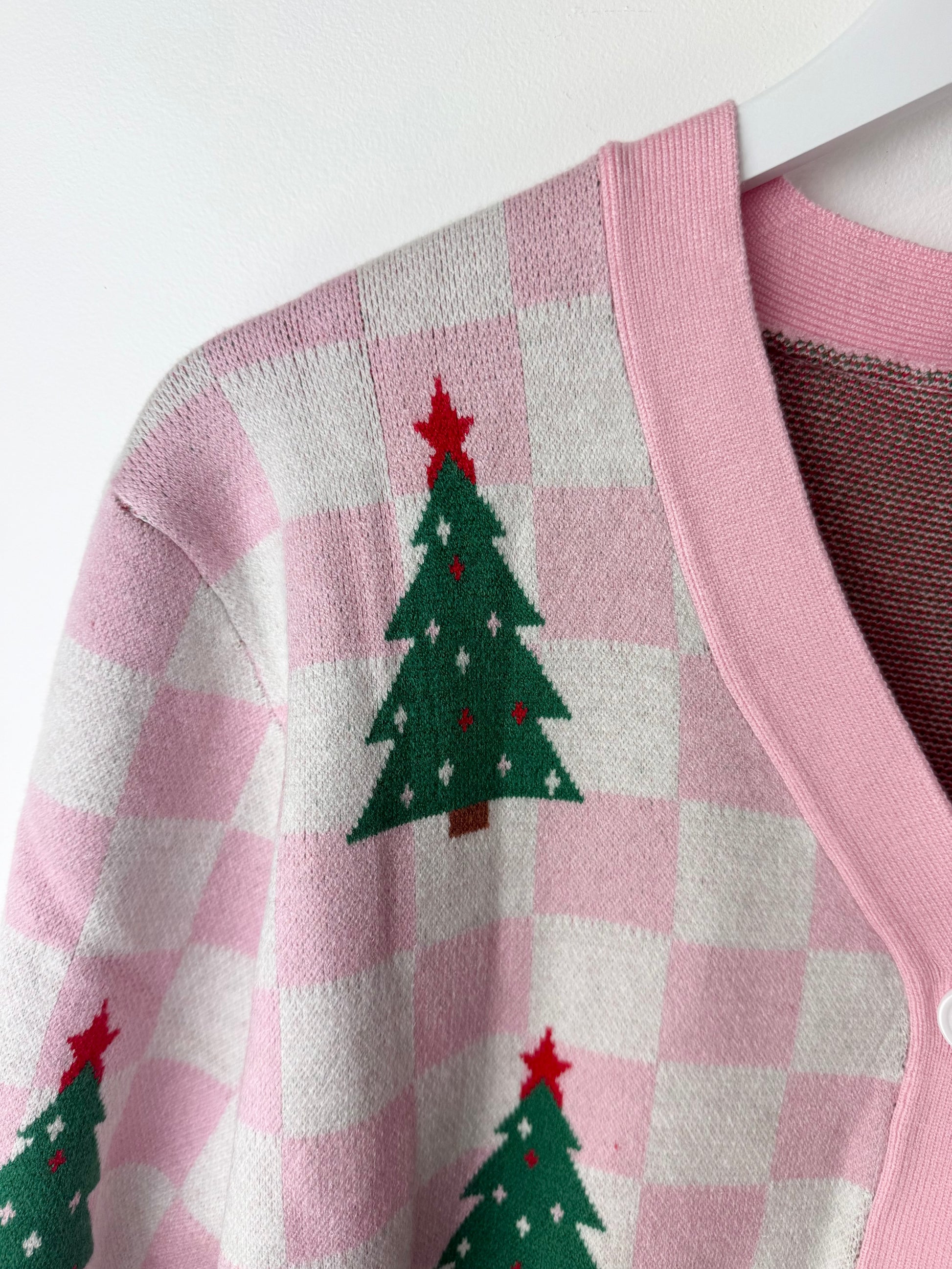 Pink checkered cardigan with green Christmas tree patterns on a white background