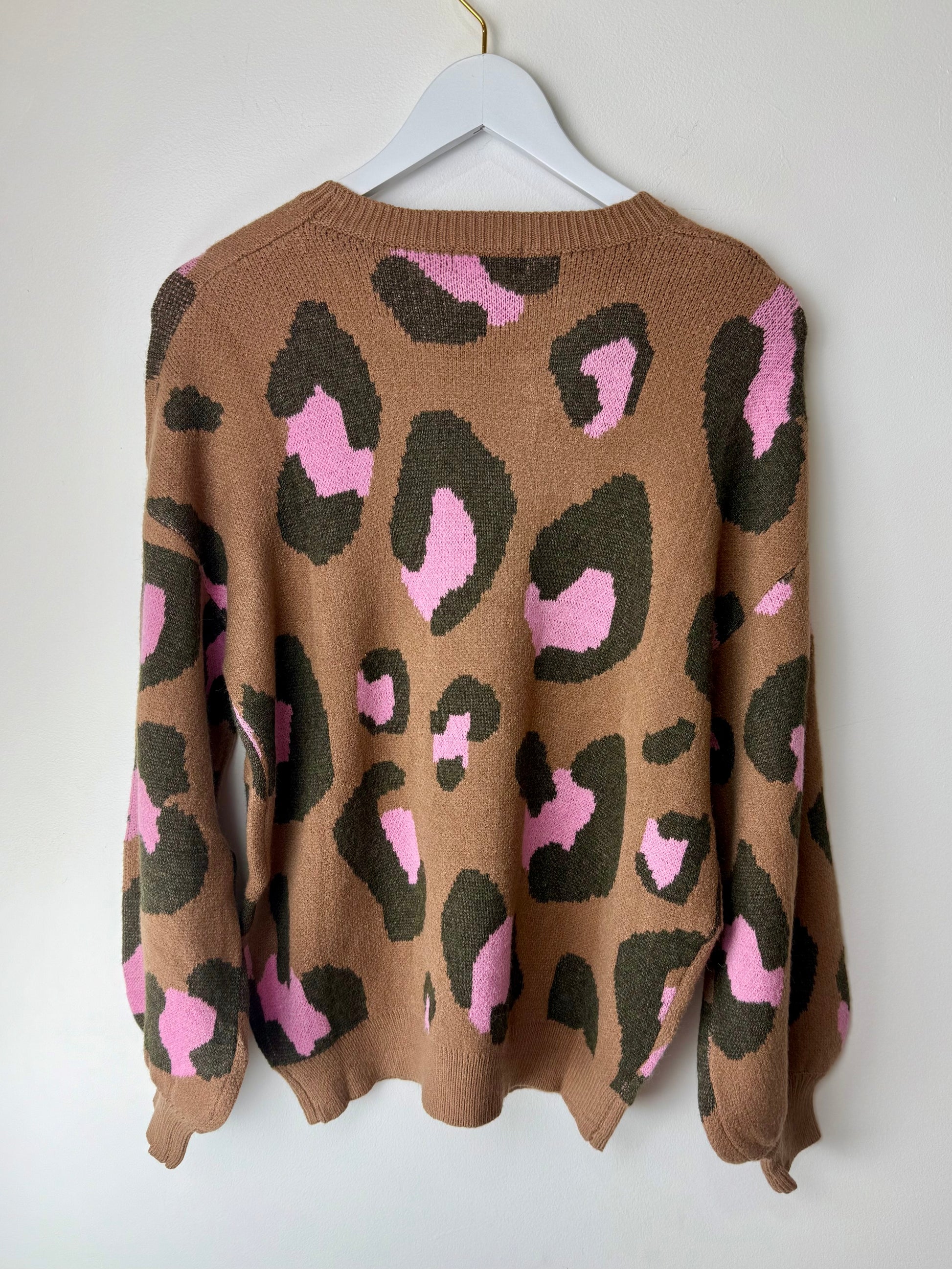 Brown sweater with pink and black leopard print on a white hanger against a white background