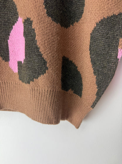 Close-up of a knitted fabric with brown, black, and pink pattern on a white background