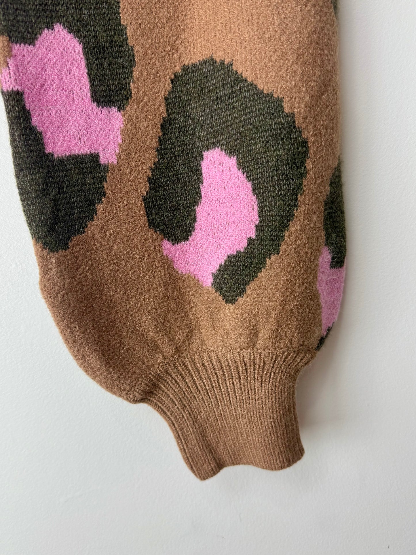 Brown knitted sleeve with pink and black abstract pattern on a white background