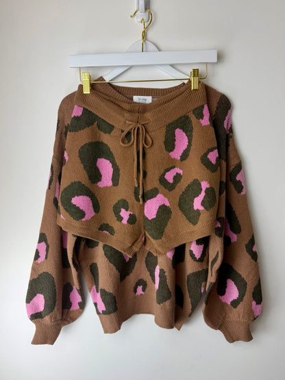 Brown sweater and shorts set with pink and green leopard print on a hanger against a white background