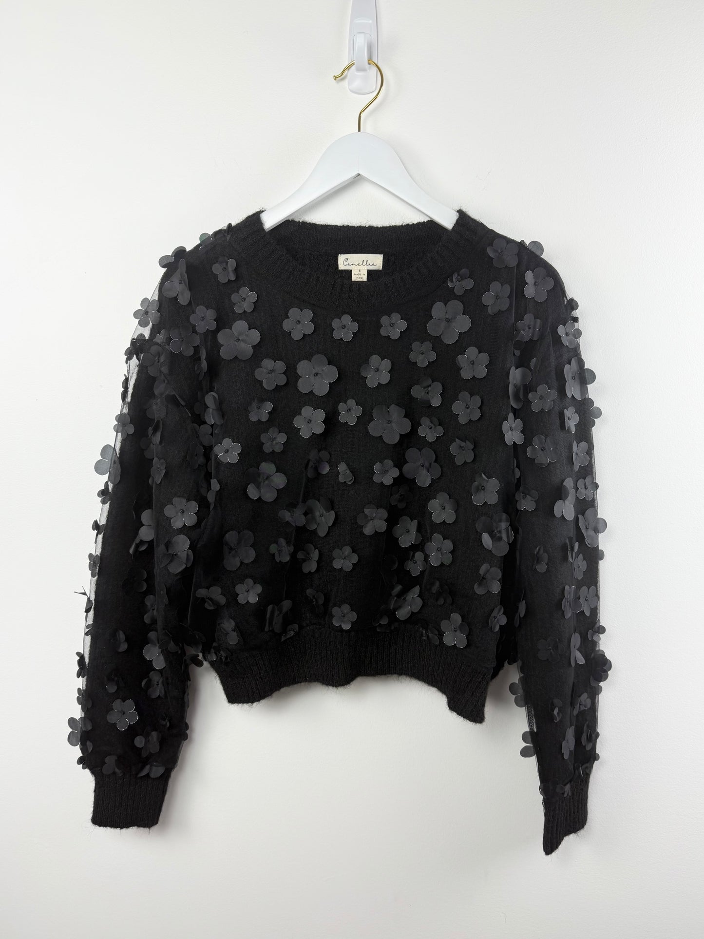 Black floral embroidered sweater on a white hanger against a white background