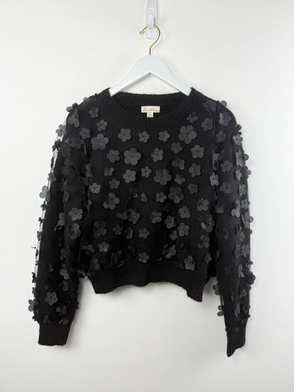 Black floral embroidered sweater on a white hanger against a white background
