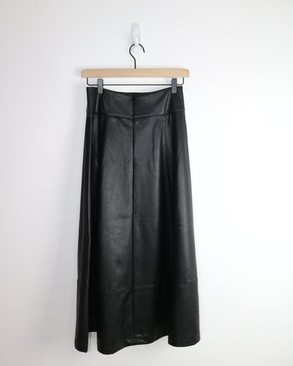black faux leather skirt hanging on a white wall