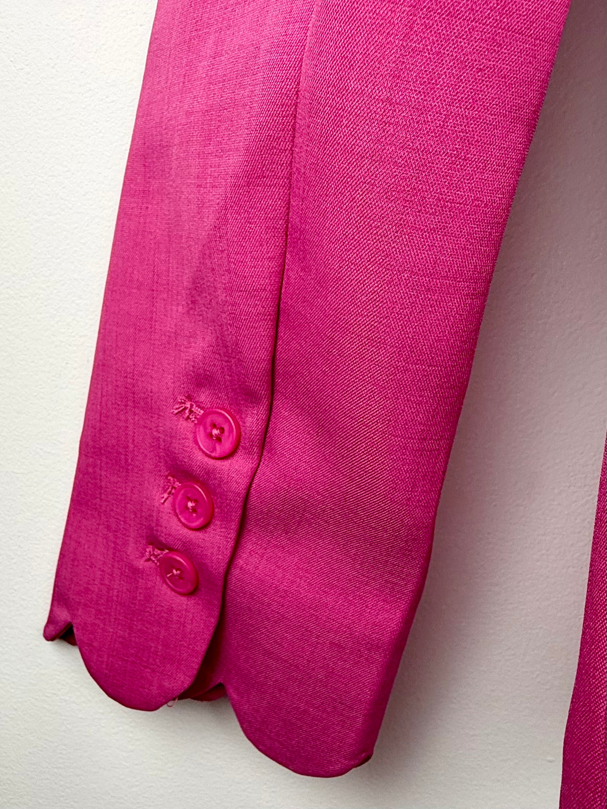 Close-up of a pink garment with buttons on a light background