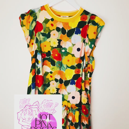 video of details of a colorful floral shift dress hanging on a white wall