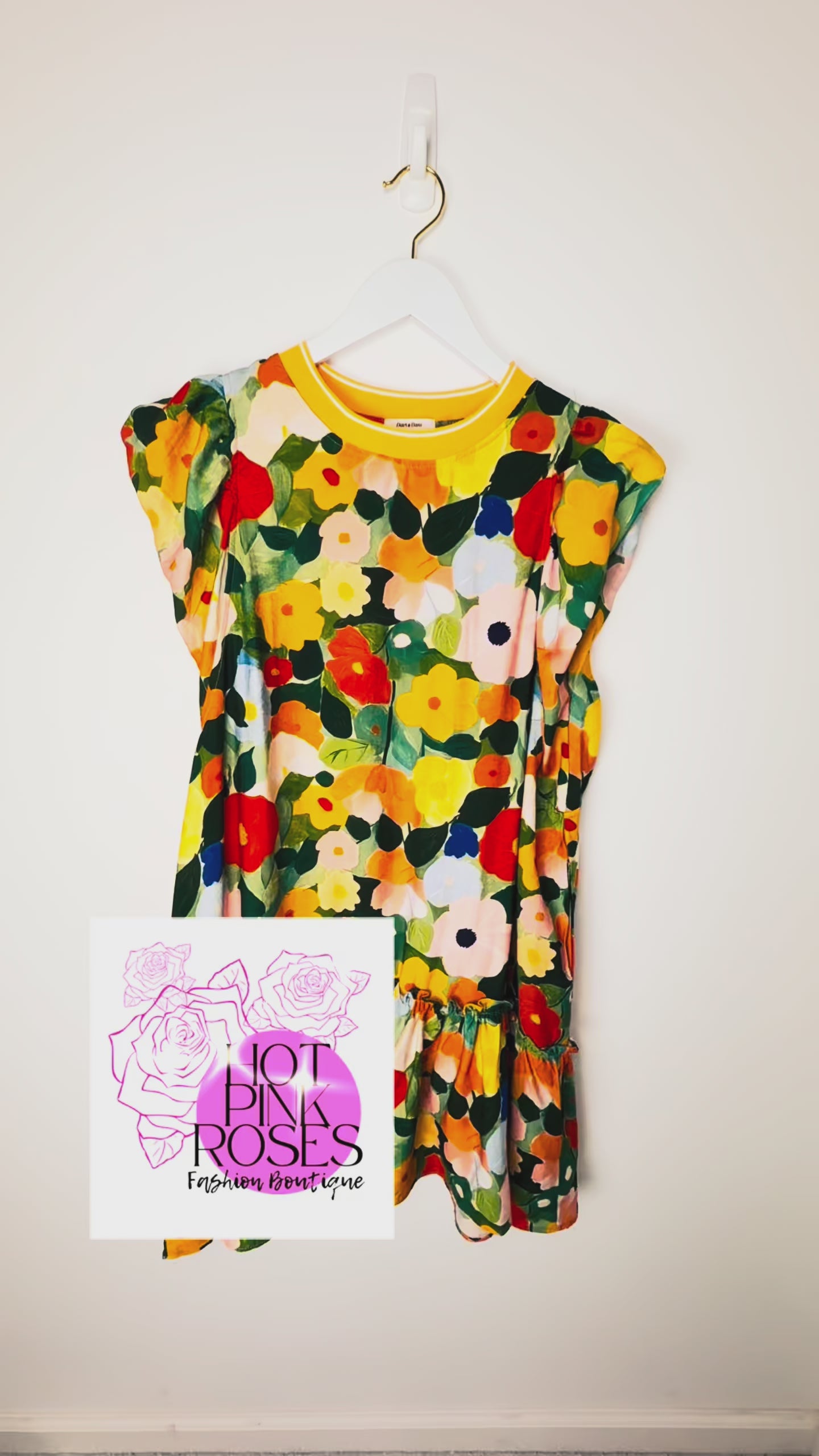 video of details of a colorful floral shift dress hanging on a white wall