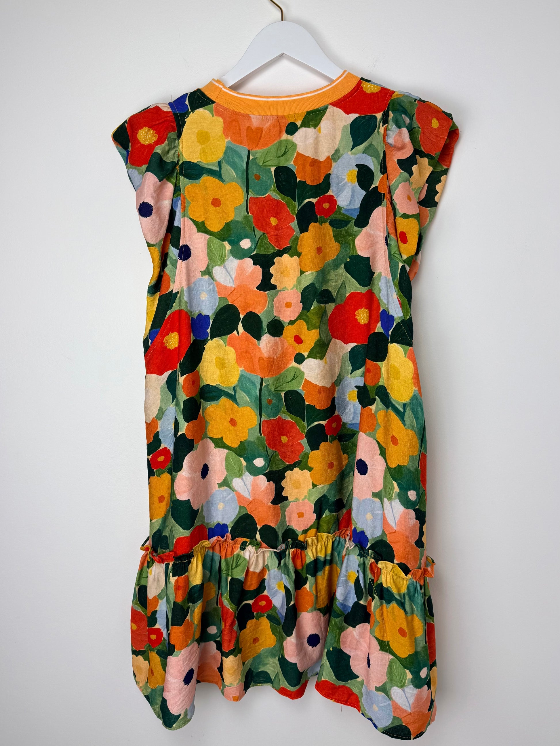 Colorful floral dress on a white hanger against a white background